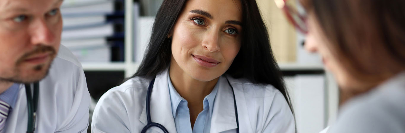 Group of GP consulting young woman in office